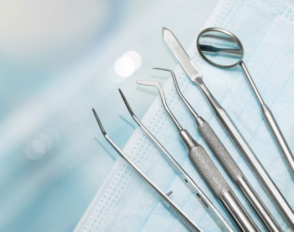 The image displays a collection of dental instruments, including forceps, on a blue fabric background with a focus on sterilization and medical equipment.