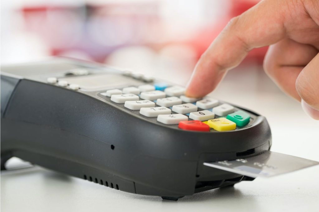 A person pressing a button on a credit card machine.